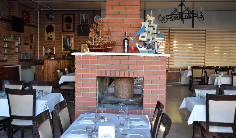 Sandal Balık Evi’nin şömineli kapalı salonu ve hazırlanmış masaları